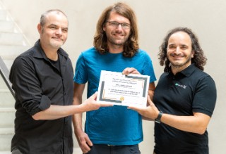 Three men holding a certificate.